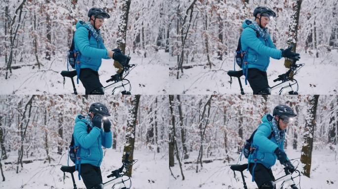 带前灯的男性骑自行车的人准备在雪道上穿越冬季森林