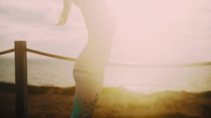日落时，无法识别的健身女运动员在海滩上伸展的手持镜头
