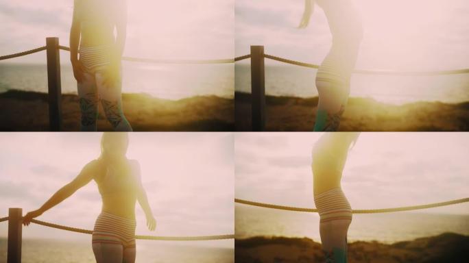 日落时，无法识别的健身女运动员在海滩上伸展的手持镜头