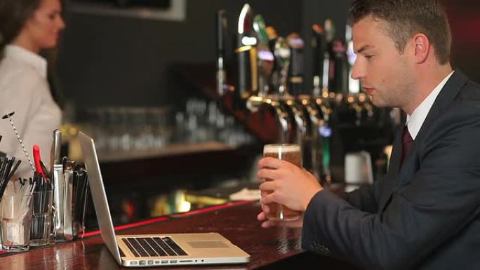 商人一边喝啤酒一边在笔记本电脑上工作
