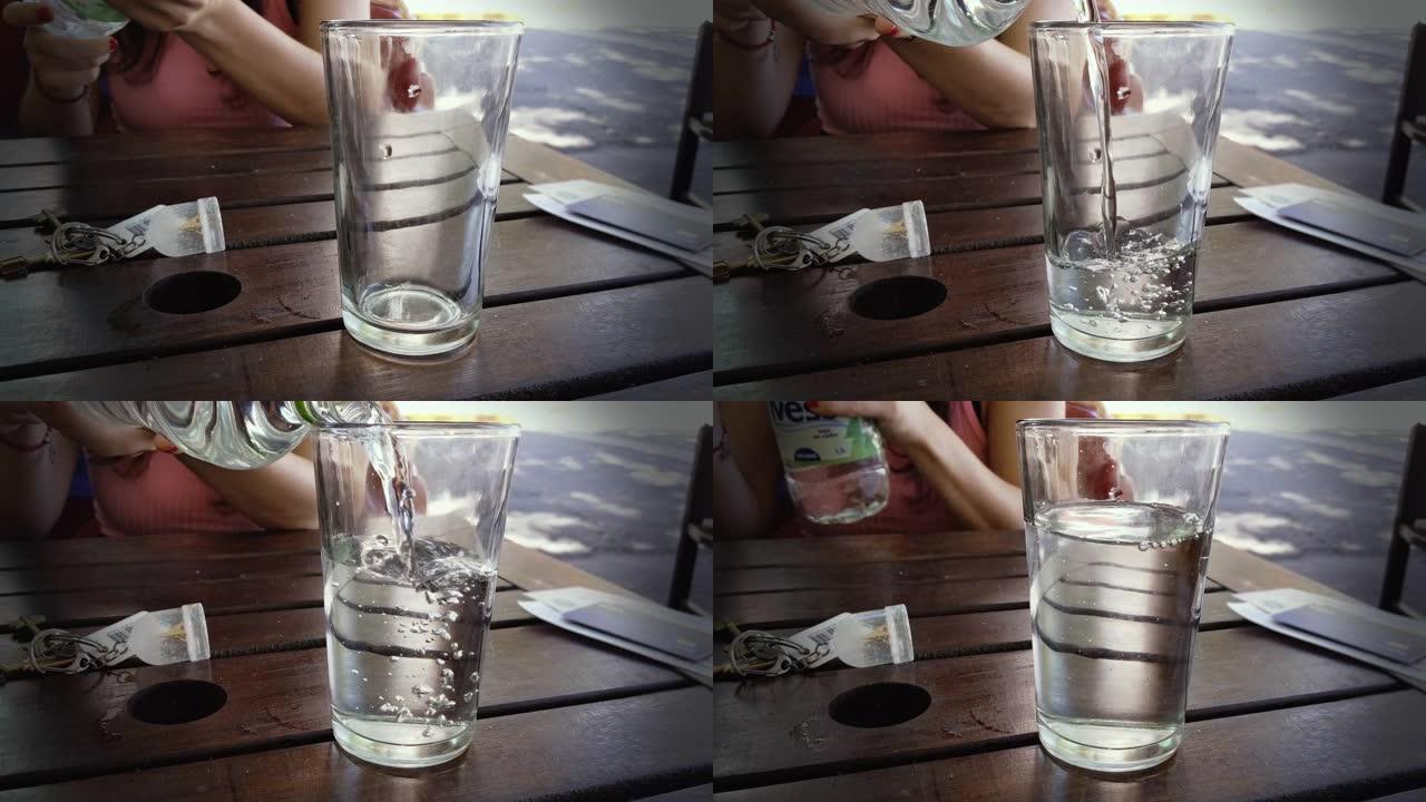 女性的手从户外酒吧的塑料矿泉水瓶中倒出新鲜的矿泉水。