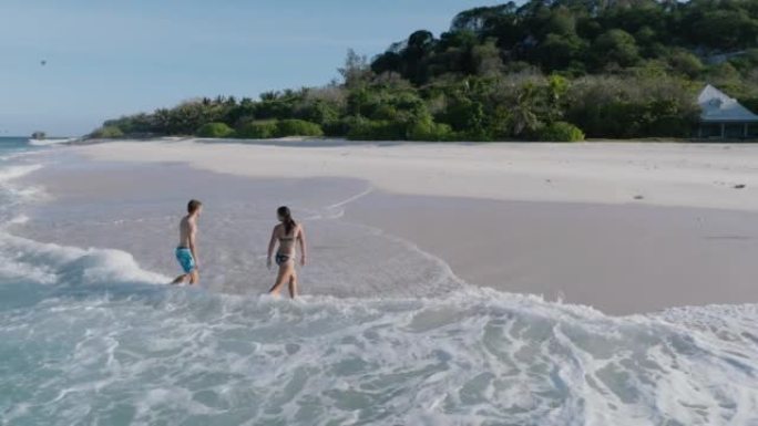 一对浪漫夫妇在塞舌尔库辛岛的私人海滩上走出大海的鸟瞰图