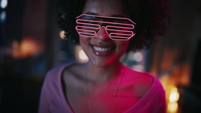 在未来的霓虹灯发光眼镜中，近距离拍摄多民族年轻的黑人拉丁女性的肖像，在家里玩得开心，晚上在阁楼公寓里
