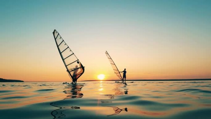 日落时，两个人在湖中滑浪风帆
