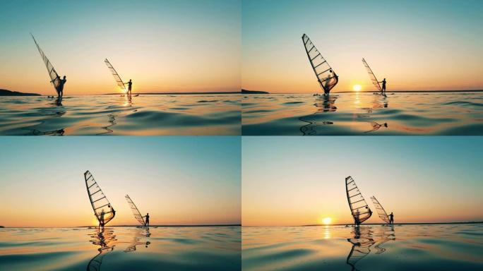 日落时，两个人在湖中滑浪风帆