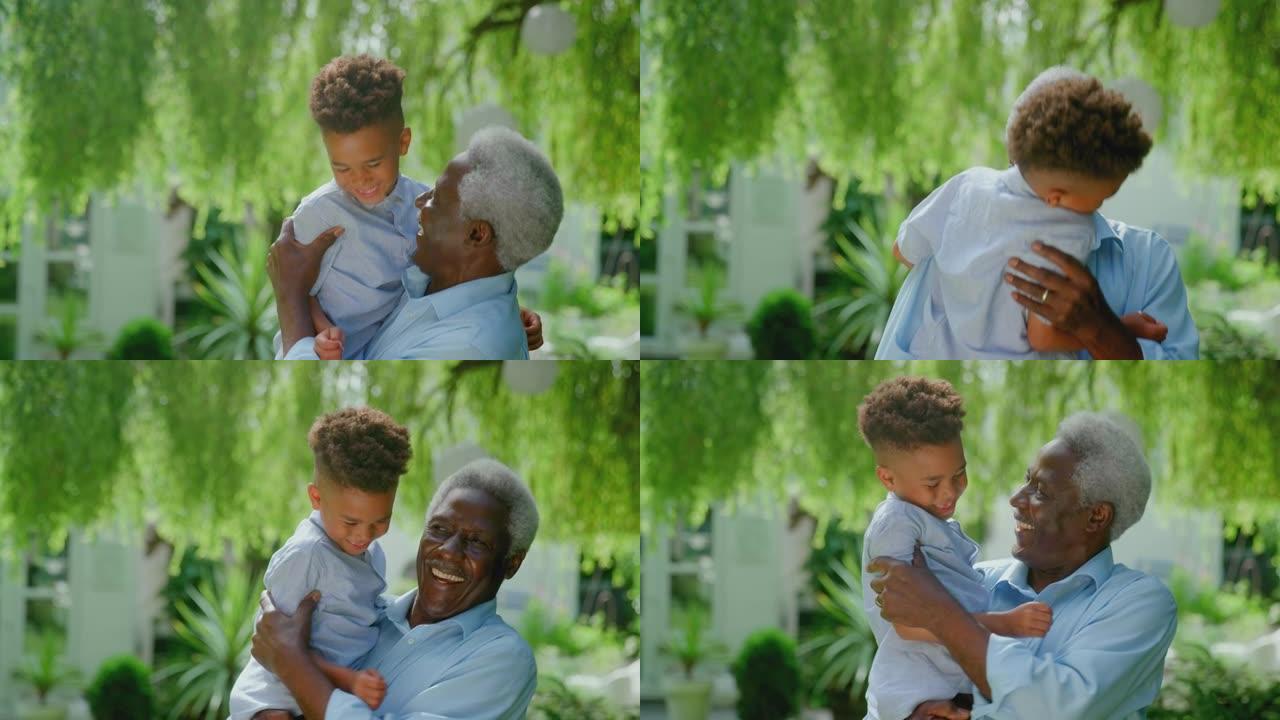 慈爱的祖父在家里的花园里怀抱孙子的肖像