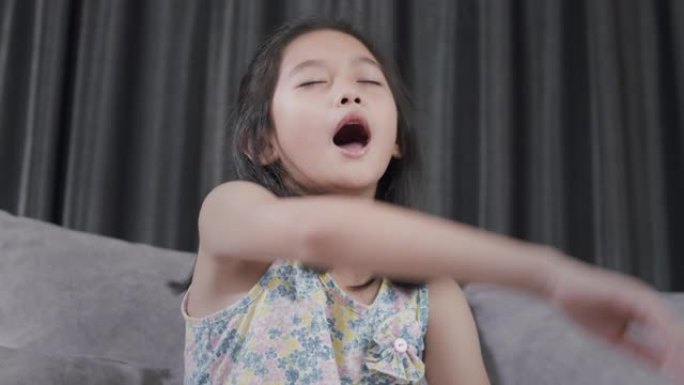 亚洲孩子打喷嚏，用餐巾纸从流感中吹鼻子。她过敏。年轻。在家中患流感的女孩
