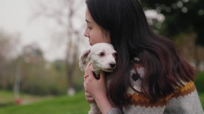 在夏日，年轻女子在户外拥抱她最喜欢的蓬松白狗。