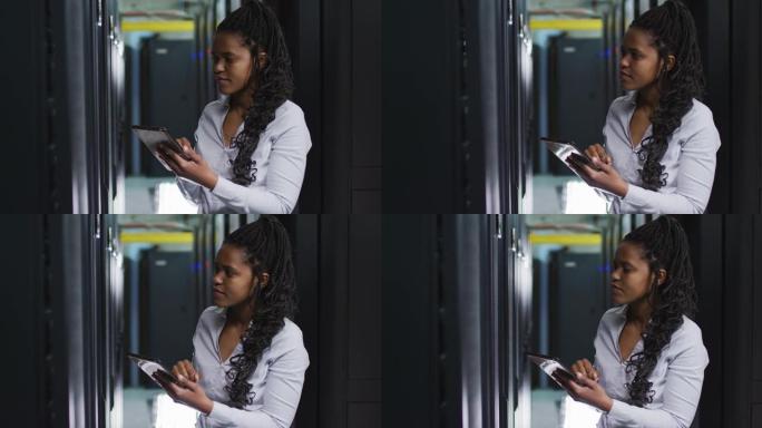 非裔美国女计算机技术员使用平板电脑在商务服务器机房工作