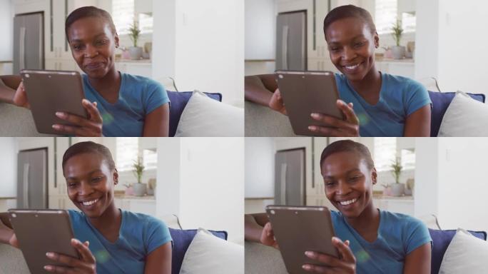 快乐的非洲裔美国女性坐在沙发上使用数字平板电脑