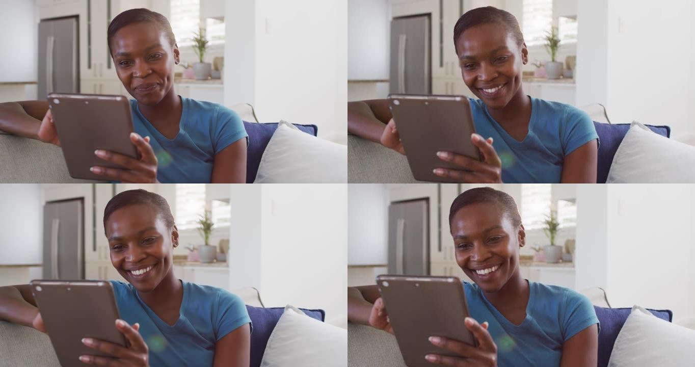 快乐的非洲裔美国女性坐在沙发上使用数字平板电脑