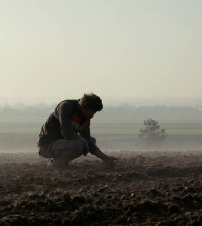 SLO MO Farmer在雾覆盖的田地上检查土壤