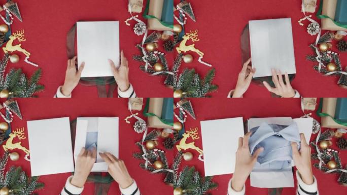 女孩手的俯视图打开礼物礼品盒红色背景的冬季圣诞装饰品。