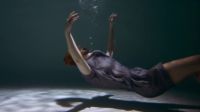 穿着睡衣的年轻美女的电影侧视图，眼罩沉入水中，睡着做梦慢动作。