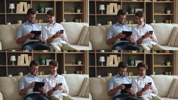 结合千禧一代双胞胎兄弟使用触摸板智能手机在沙发上放松