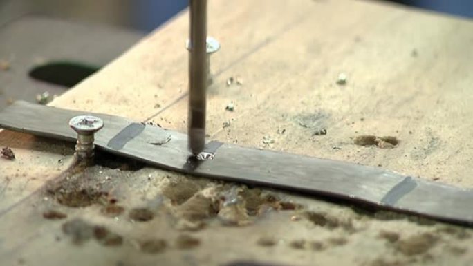 工人在他的车间制造Yerba Mate葫芦时，用台钻在金属上钻孔。特写。