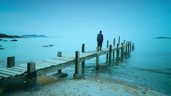 男子在海岸线的木制人行道上行走