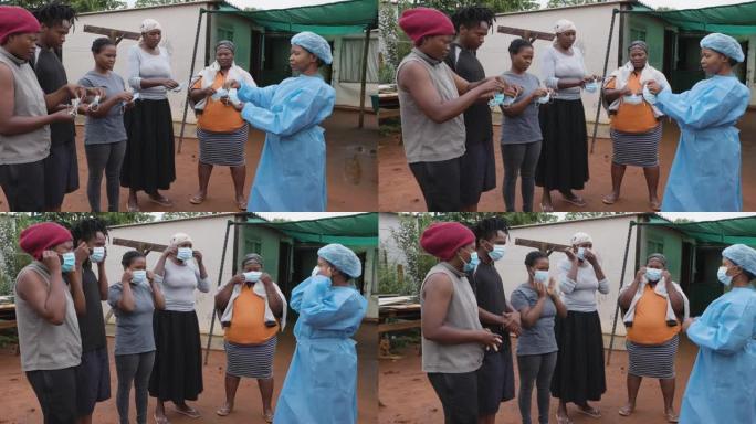非洲黑人女护士向农村居民点的人们演示如何戴上防护口罩，以预防Covid-19