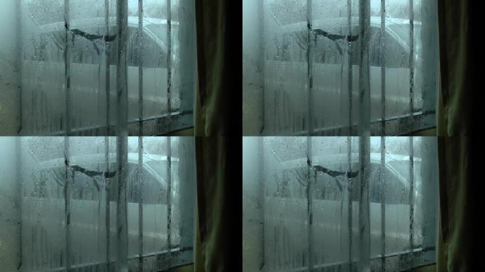 窗户上的水滴，房屋内窗户玻璃上的水滴，背景中停放的汽车。特写。