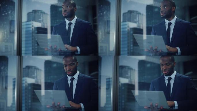 成功的黑人商人的肖像穿着西装站着，用笔记本电脑看着办公室窗外。微笑股市投资经理与电脑合作从外面拍摄