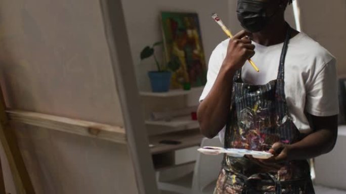 体贴的非洲裔美国男性艺术家在艺术工作室拿着画笔和调色板