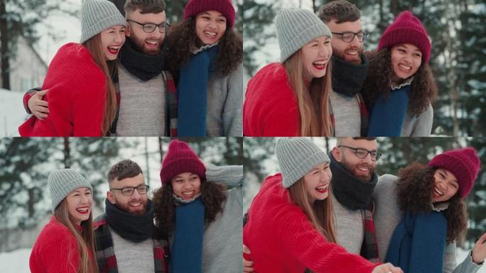 快乐微笑的多民族男人和两个女人挥舞着，在假期慢动作的白雪皑皑的冬季森林里兴高采烈地摆姿势。