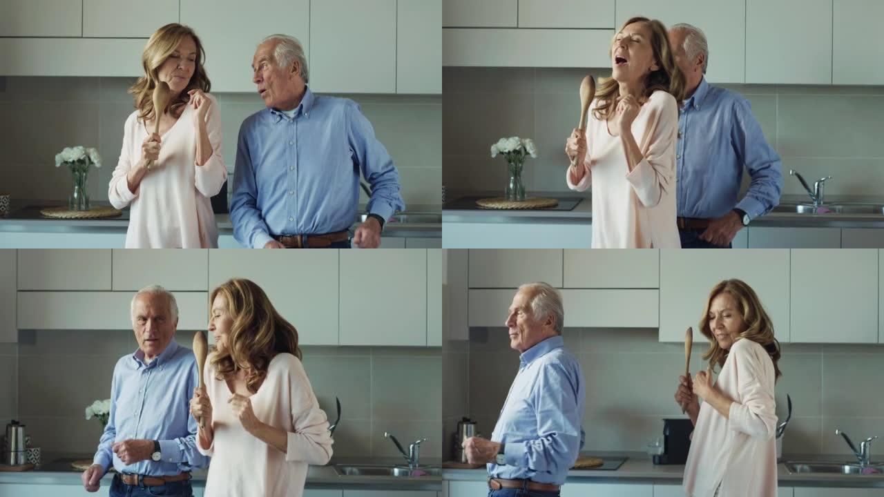 在家里的厨房里，快乐的成熟的高级夫妇享受着一起唱歌跳舞庆祝他们永恒的爱情的电影镜头。概念: 爱情，家