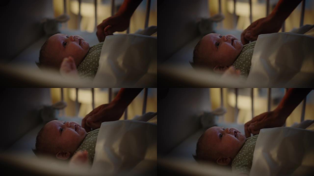 真实的特写镜头，一位母亲在婴儿床中抚慰并牵着新生婴儿的手。白人新生儿蹒跚学步的孩子在孩子们的卧室里。
