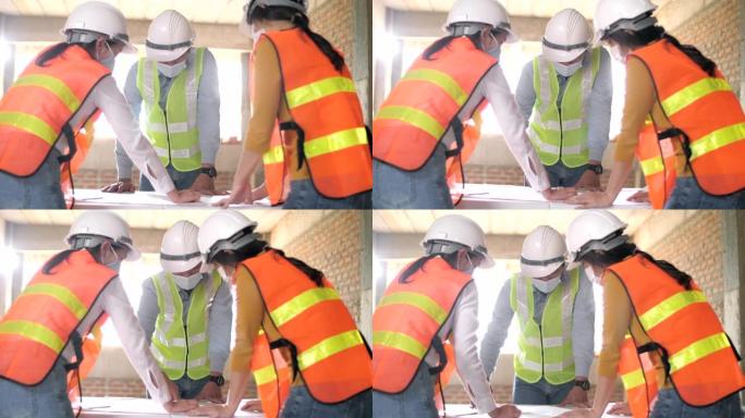 带防护面罩的工人在施工现场工作及蓝图中的讨论
