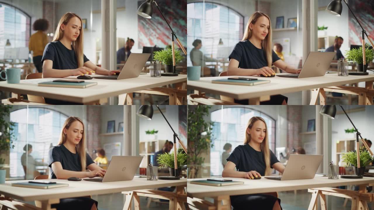穿着黑色休闲装的美丽女性坐在创意办公室的办公桌前，在笔记本电脑上处理任务。年轻的创意专家为营销议程撰
