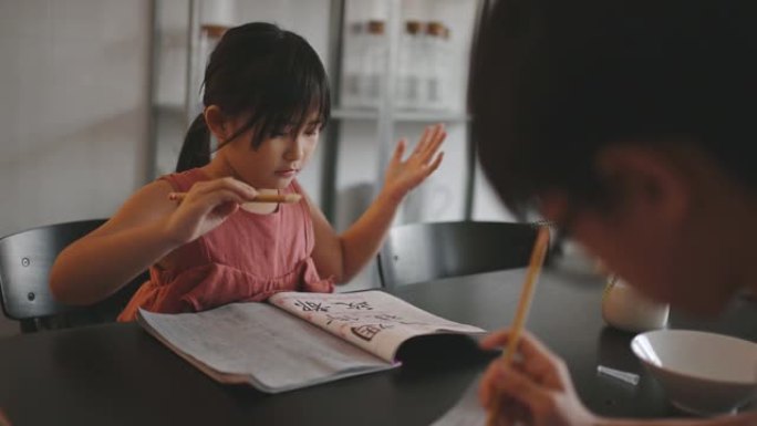 2在家学习的幼儿在餐厅写中国书法