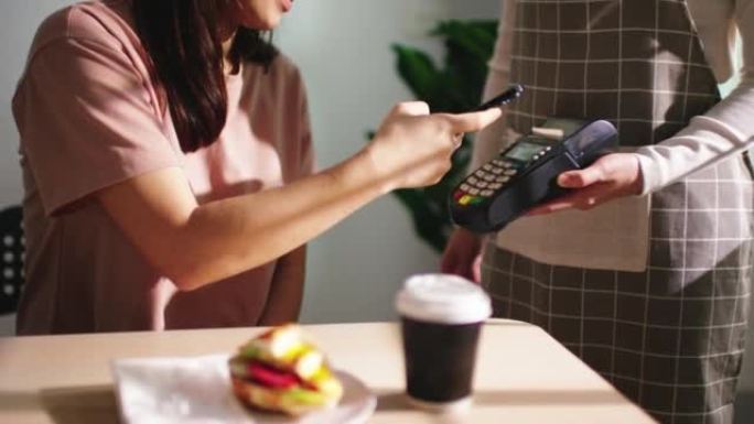 餐厅的女顾客使用智能手机支付账单