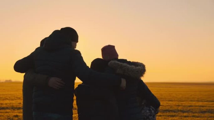 日落时在草地上拥抱三个孩子的SLO MO爱心家庭