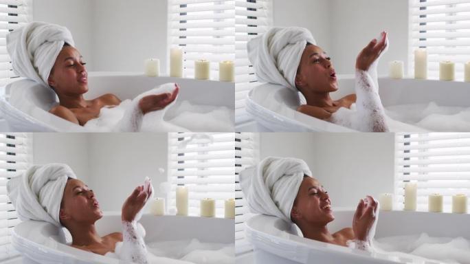非裔美国妇女在家里浴室的浴缸里吹肥皂泡