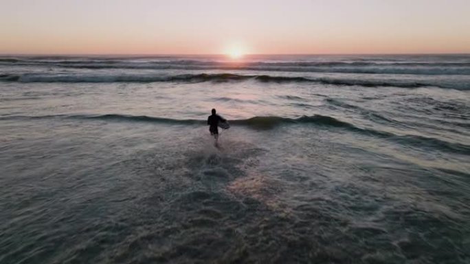 空中背光的日落美景，冲浪者闯入海浪冲浪