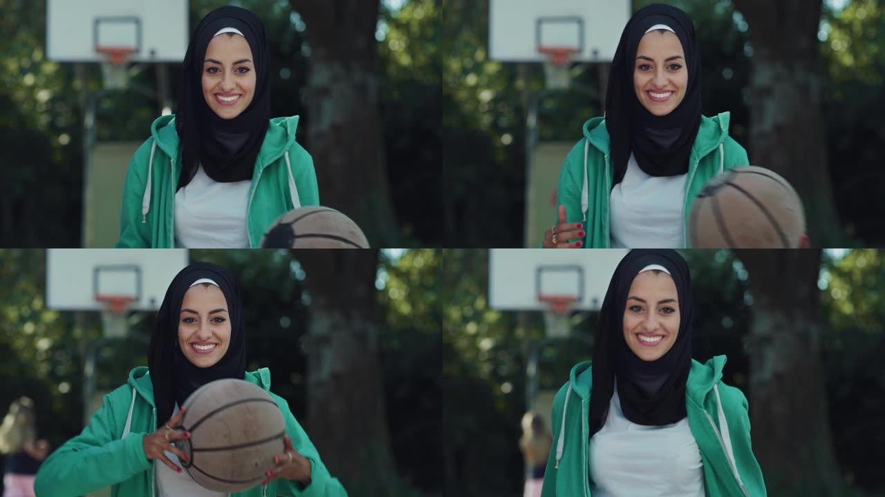美丽的穆斯林年轻女子在看着相机时扔篮子球的肖像。戴着头巾的女运动员无视刻板印象，追随自己的职业梦想