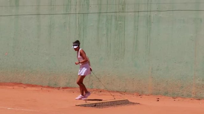 女子网球运动员在网球练习前清洁红土球场