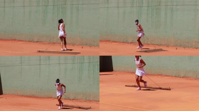 女子网球运动员在网球练习前清洁红土球场