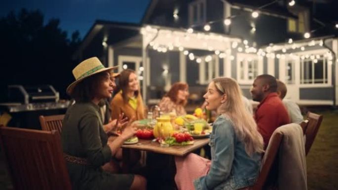 大家庭花园之夜聚会庆典，与亲朋好友聚在一起。缩小年轻人和老年人吃喝玩乐的镜头。