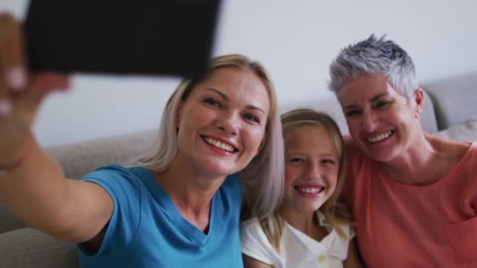 高加索祖母，母亲和女儿在家里用智能手机自拍时微笑