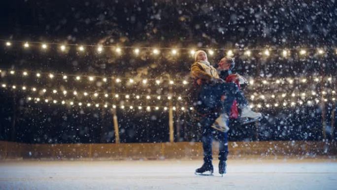 浪漫的冬天下雪的夜晚: 滑冰夫妇在溜冰场上玩得开心。双人滑冰boyfried抬起他美丽的女友并旋转。