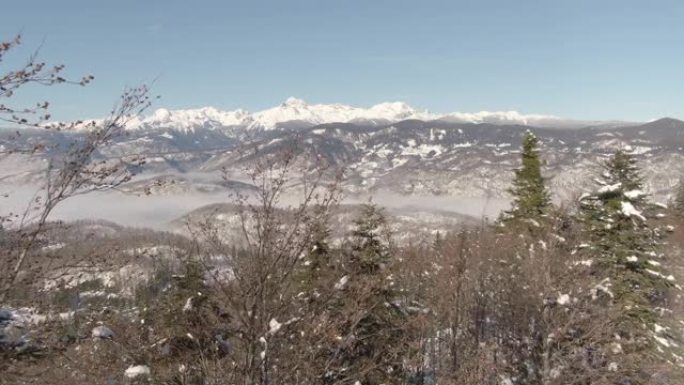 空中: 风景如画的无人机在白雪皑皑的朱利安阿尔卑斯山的雾蒙蒙的山谷中。