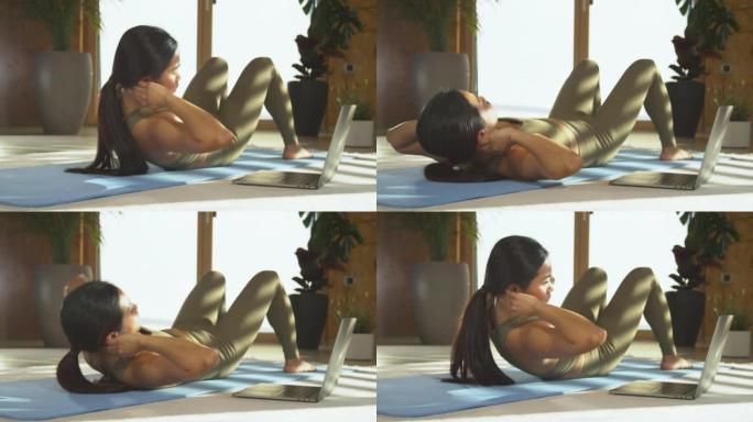年轻的亚洲女性观看在线锻炼视频并进行腹肌锻炼