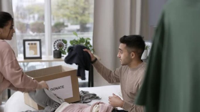 一对年轻夫妇在家坐在捐款箱旁整理衣服的4k视频片段