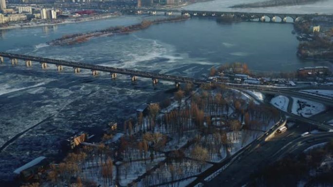 令人惊叹的空中全景，汽车在寒冷的日出基辅的长桥上驶过冰冷的冬季第聂伯河