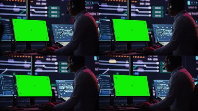 专业的信息技术技术支持专家和软件开发人员在数字屏幕监控控制室的绿屏模拟显示计算机上工作。员工戴上耳机