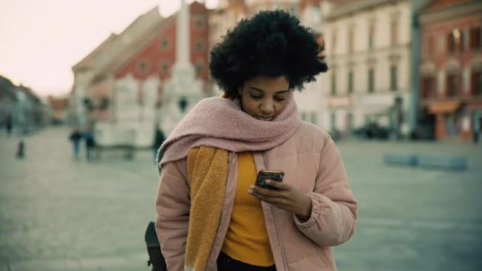 一名年轻黑人妇女的肖像照片在城市使用她的智能手机