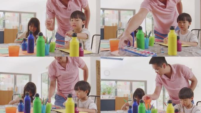 亚洲父亲与孩子们在家里的桌子上做手艺玩得开心