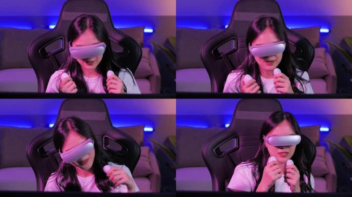 亚洲少女头戴虚拟现实头戴式耳机，一边坐在办公桌前，一边用操纵杆/控制器打手势。夜间在彩色紫外线照明客