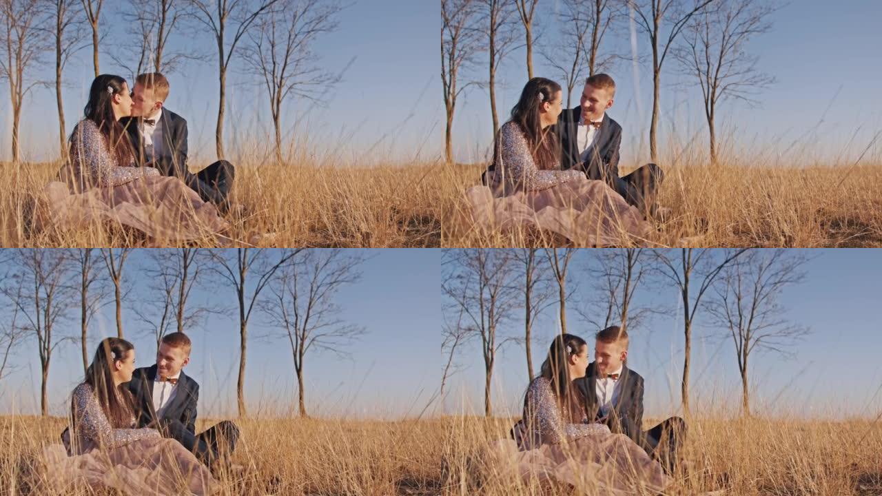 快乐的新娘和新郎坐在草地上互相亲吻